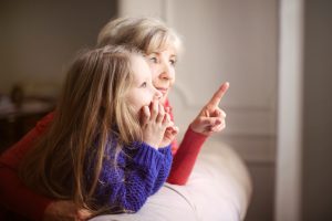 petite fille et grand-mère en train de regarder par la fenêtre